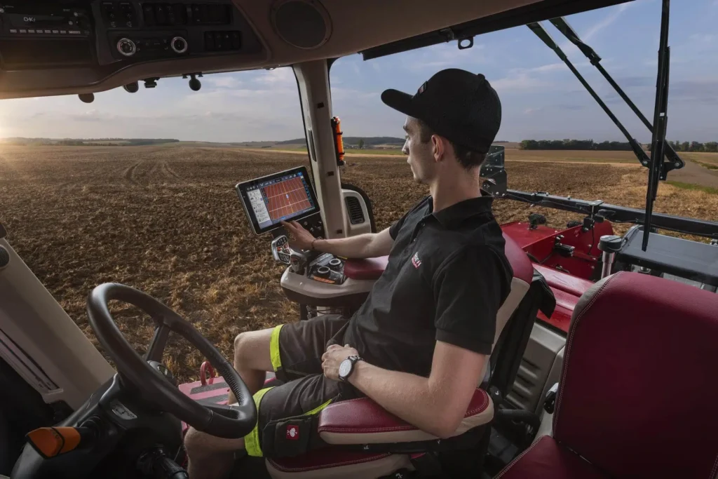 Fører inne i en Case IH traktor, ser på en avansert skjerm som viser data om feltarbeid.