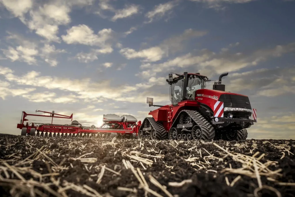 Case IH Quadtrac 645 traktor med såmaskin på et jorde under en blå himmel med skyer.