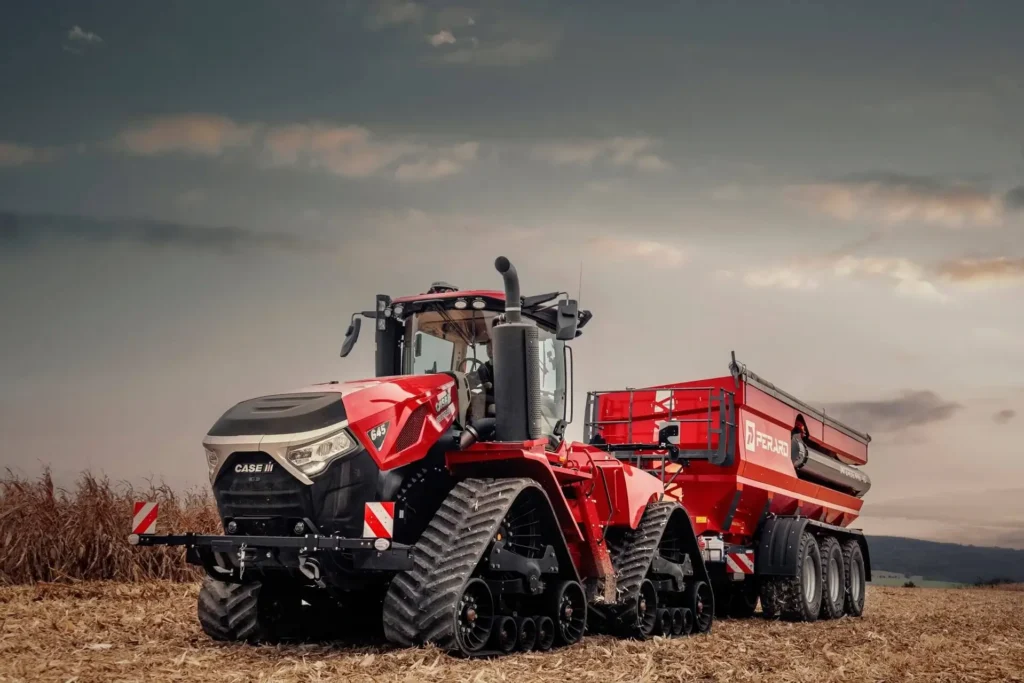 Case IH Quadtrac 645 traktor med en stor rød henger koblet bak, under en dramatisk kveldshimmel.