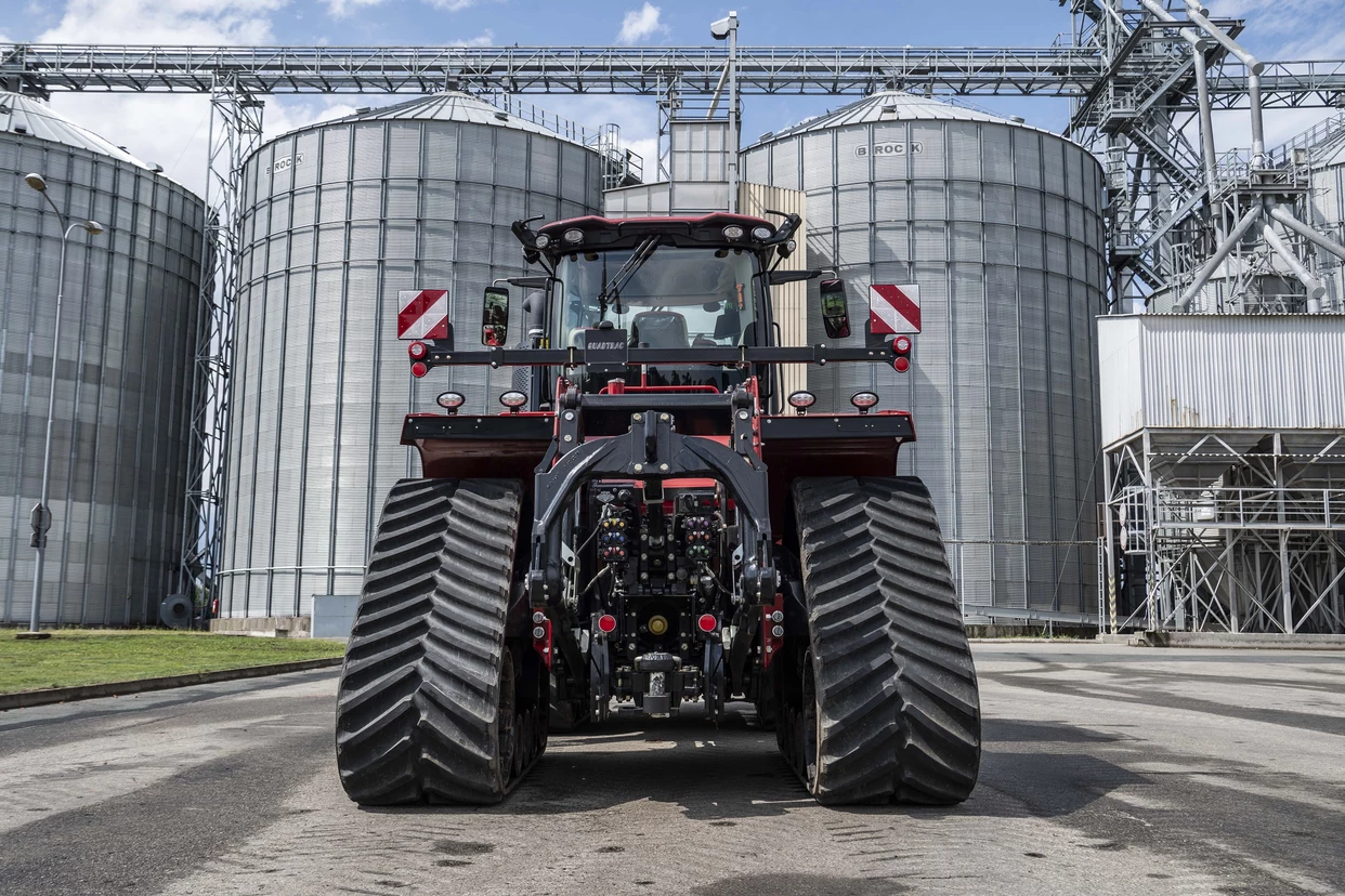 Case IH Quadtrac 715 AFS Connect™ ved siloer – Bakbilde av traktoren parkert foran store kornsiloer, viser dens robuste design.