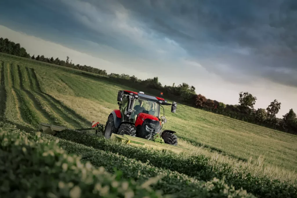 Case IH Vestrum traktor med Krone slåmaskin på grønn eng.