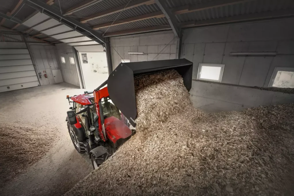 Case IH Vestrum traktor i en lagerbygning som laster flis.