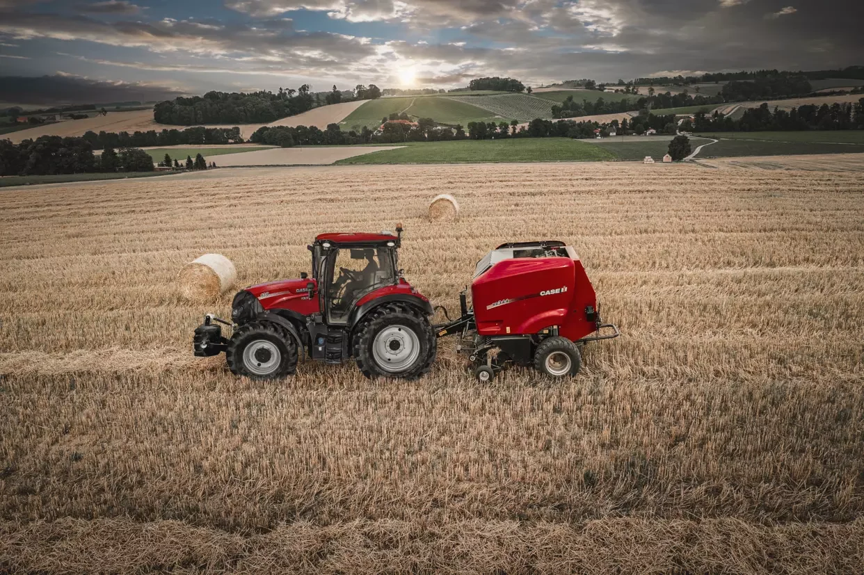 Case IH Vestrum traktor koblet til en rundballepresse i en gyllen åker.