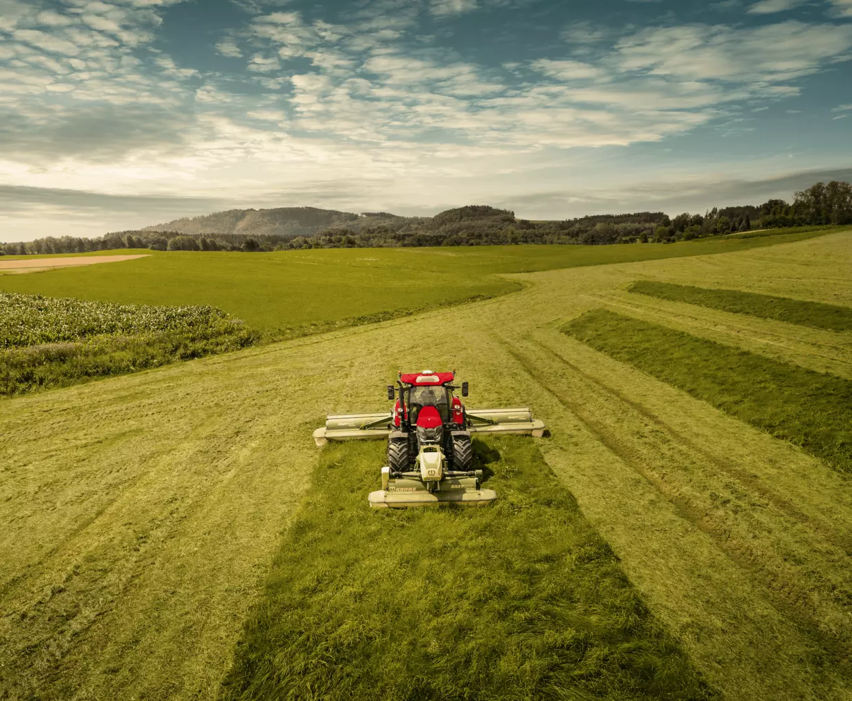 Case IH Puma traktor i arbeid med slåmaskin på en grønn eng