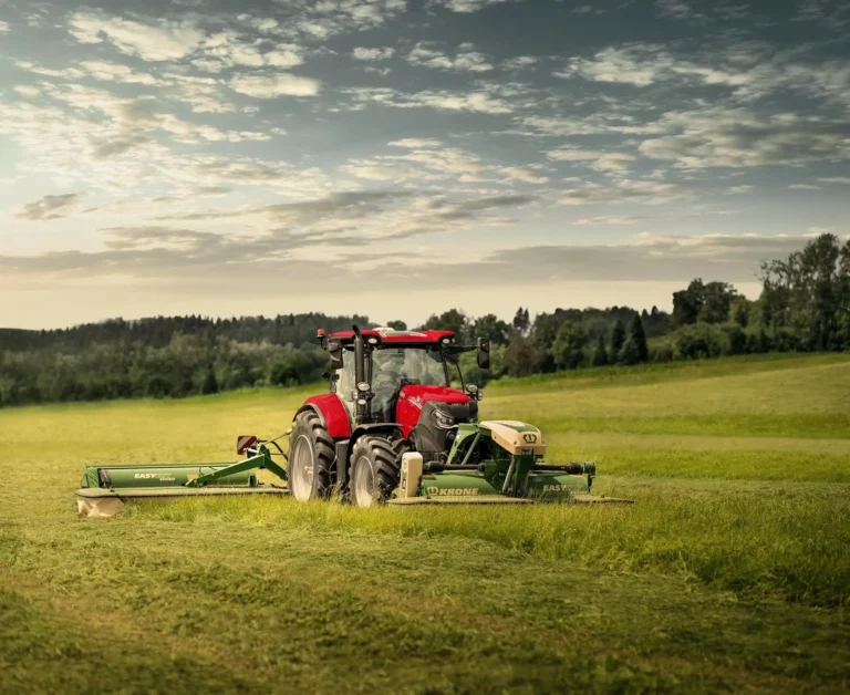 Case IH Puma kjører på jorde, med slåmaskiner fra Krone.