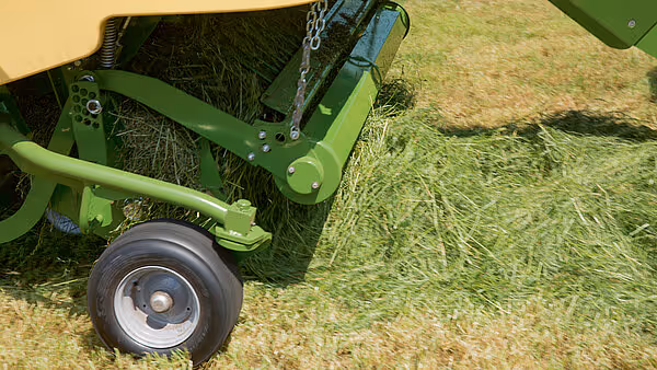 Hjul og understellsdel av kartoffelskuff med grønn farge, vist fra siden på pløyd jord.