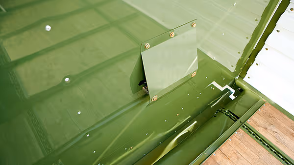 Grønt metallkammer med monteringsplater og skruer på KRONE AX høyladervogn.