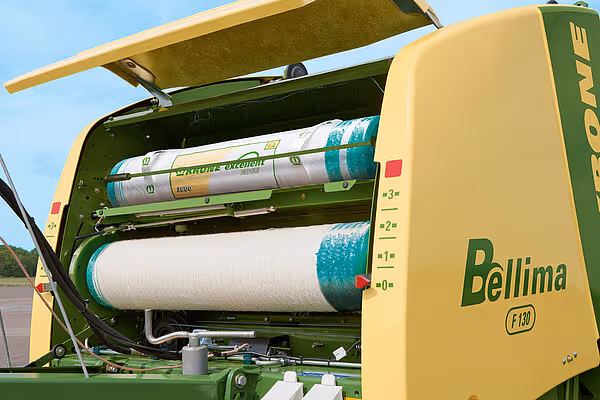 Åpen nettkammer på en KRONE Bellima rundballpresse som viser to ruller med blått og hvitt plastnett for innpakning av rundballar.