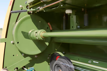 Grønn aksel og lager på en KRONE rundballpresse, som er del av maskinens roterende system for ballforming.