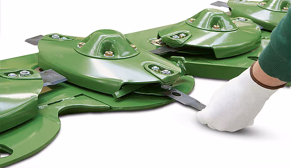 Nærbilde av slåskivene på KRONE Big M 450 fra siden, som viser de grønne slåskivene med tilhørende kniver og festeanordninger. Slåskivene er montert på maskinens slåbord.