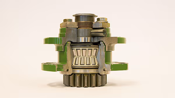 Tverrsnitt av girkasse eller kraftoverføringsenhet fra KRONE Big M 450, som viser indre tannhjul og lagerkomponenter. Enheten har grønne støtteelementer.