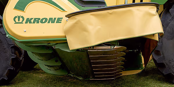 Krone slåmaskin med gul og grønn fargekombinasjon, viser frontdelen med merkelogo og deler av slåverket.