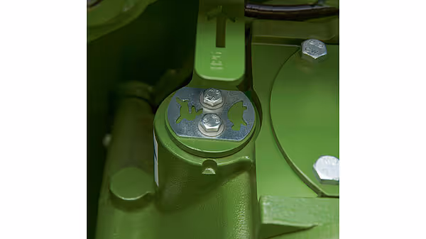 Nærbilde av monteringspunkt for slåskive med synlige bolter og grønn lakkeringsfinish.