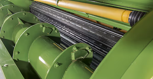 Nærbilde av slåttemekanismen på KRONE Big M 450 med sorte slåttekniver og grønne maskinkomponenter.