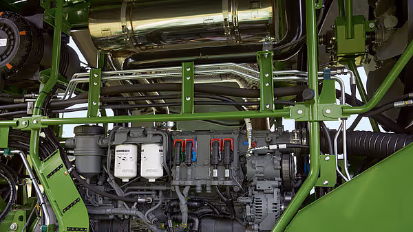 Motorkupé på Krone Big M 450 med åpent motorlokk som viser kompleks rørledningssystem. Hydraulikkrør, luftrør og elektriske komponenter er organisert langs grønt maskinramme.