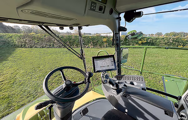 Førerkabine i Krone Big M 450 med ratt, instrumentpanel og stor touchskjerm montert på konsoll. Store vinduer gir god sikt over arbeidsområdet.