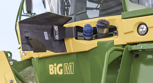 Kontrollpanel på siden av en KRONE Big M 450 slåmaskin med ulike knapper, brytere og tilkoblinger for betjening av maskinen. Panelet er montert på den gule karosseridelen.