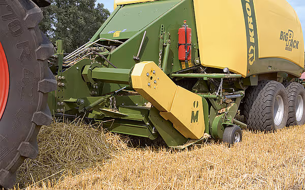 Nærbilde av Krone BigPack rundballerens oppsamlingsmekanisme som samler opp halm fra bakken.