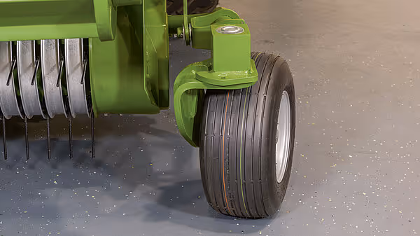 Støttehjul på KRONE storballpresse med grønt chassi og svart gummihjul på betongunderlag.