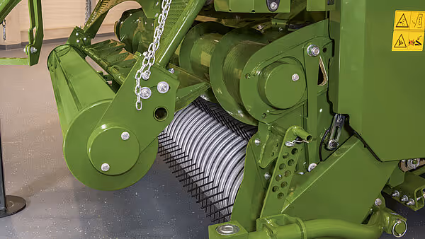 Oppsamlingsvalse med metallpigger på grønn KRONE Big Pack pressemaskin. Valsen samler opp høy og fôr fra bakken.