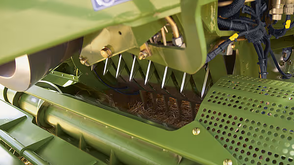 Innmatingssystem med kuttpresse og perforert deksel på KRONE BigPack Gen 5 storballpresse. Roterende kniver og innmatingsmekanisme synlig i grønn lakk.