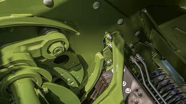 Innvendige drivhjul og kraftoverføringssystem på KRONE BigPack storballpresse. Grønne metallkomponenter med hydrauliske slanger og bolter.