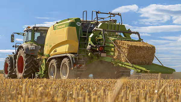 Krone Big Pack ballepresse arbeider på kornåker og produserer store firkantballer av halm. Maskinen har karakteristisk grønn og gul fargekombinasjon.