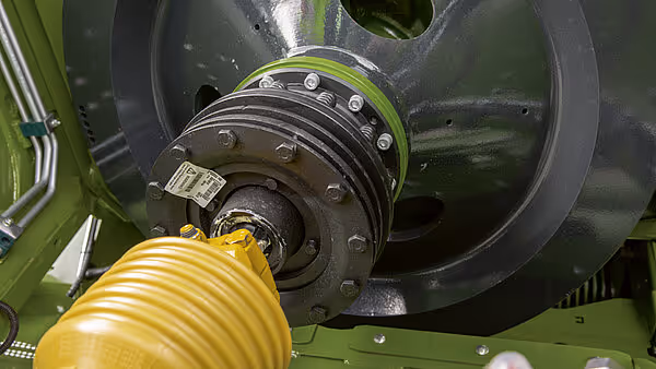 Kraftoverføringssystem med remskive og gul PTO-aksel på Krone Big Pack ballpresse. Systemet driver hovedmekanismen i maskinen.