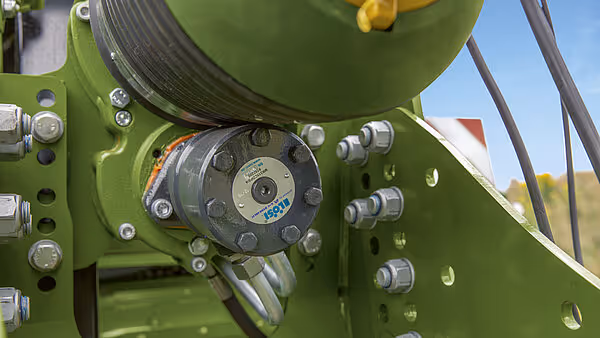 Nærbilde av hydraulisk motor og drivsystem på grønn Krone BigPack ballpress, med synlige hydraulikkslanger og monteringsbolter.