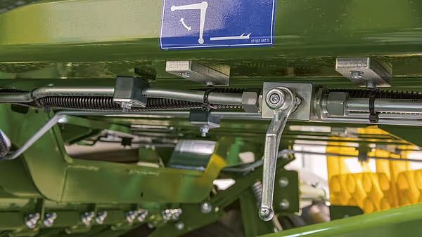 Detaljbilde av innvendige mekanismer i ballpressen, med synlig knivverk og pressingssystem for komprimering av halm.