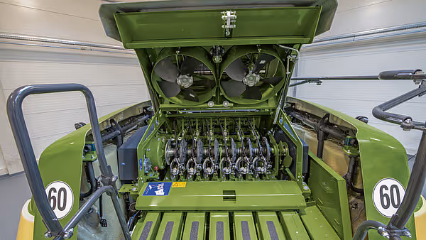 Detaljert innblikk i KRONE BigPack pressemaskins indre mekanisme med åpen topp som viser knoter- og garnsystem. Grønne metallkomponenter og pressevalser er tydelig synlige.