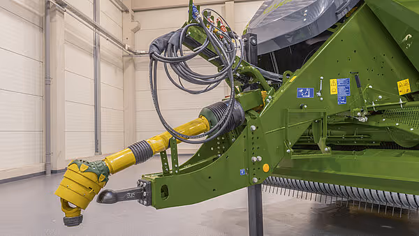 Grønn KRONE BigPack Generation 5 rundballpresse med gul hydraulisk pickup-enhet og kabelføring.