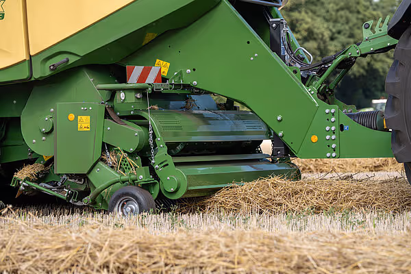 En grønn Krone Big Pack HDP II storballpresse i arbeid på en åker, med oppsamlet halm som kommer ut av maskinen.