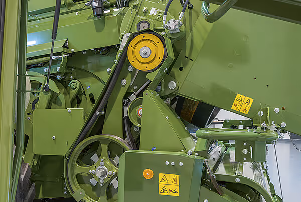 Innvendig mekanisme i KRONE Big Pack HDP II storballpresse med gul remskive og grønne deksler med advarselsskilt.