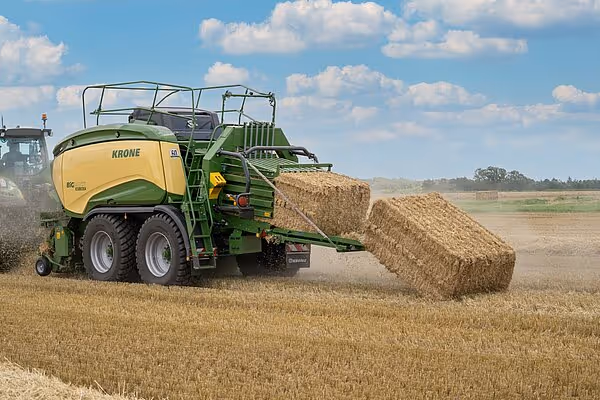 KRONE Big Pack HDP II rundballpresse i arbeid på stubbeåker, med ferdig presset rundball som rulles ut bak maskinen.