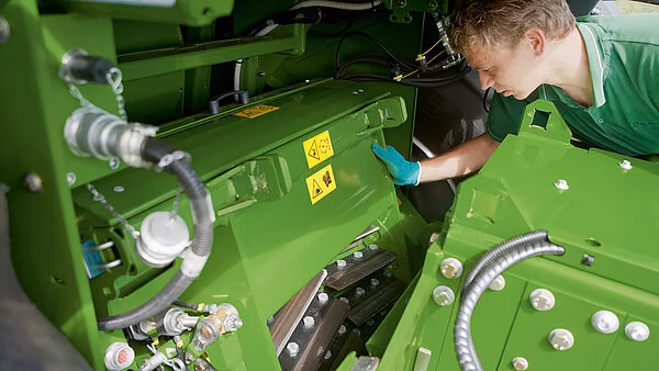 Tekniker som åpner og inspiserer inntakssystemet på en Krone finsnitter for tilgang til kuttertrommel og motkniv.