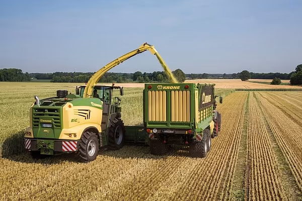 Krone Big X som fyller tilhenger som kjører ved siden av maskinen.