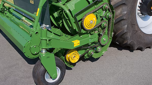 Nærbilde av KRONE EasyFlow pickup-mekanismens drivverk og kjettingdrev med gul tannhjulaksel.