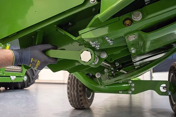 Tekniker justerer glideskiene på undersiden av KRONE XDisc 710 skjærebord.