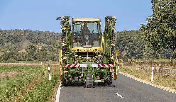 KRONE BiG X felthøster med EasyCollect i transportposisjon på landevei med ekstra løpeverk.