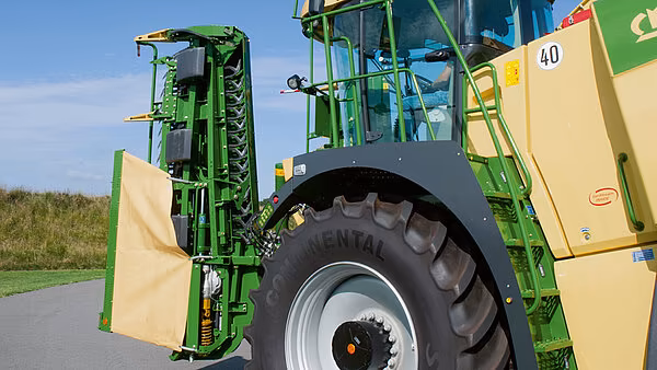 KRONE EasyCollect todelt maishøstehode i transportposisjon langs siden av felthøsteren på landevei.