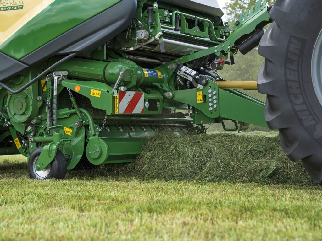 KRONE CombiPack HDP rundballepresse koblet til traktor på en grønn eng, fotografert fra lavt vinkelpunkt.