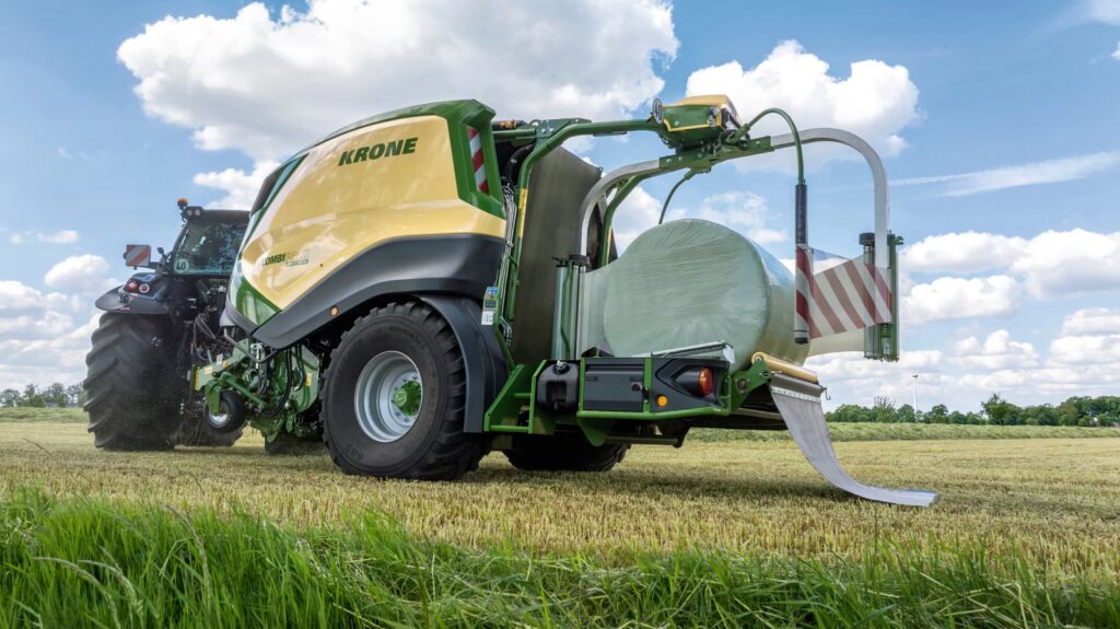 Bakpartiet på KRONE CombiPack HDP CV 165 XC med åpen ballekammer, fotografert på eng med vindmølle i bakgrunnen.