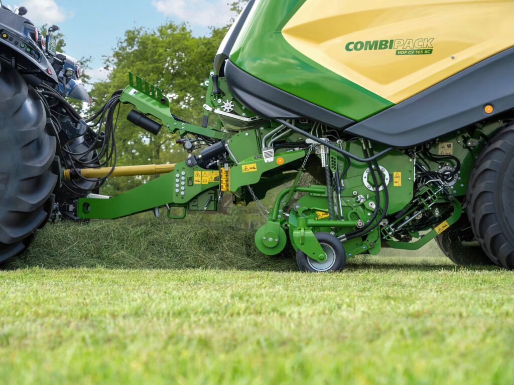 KRONE CombiPack HDP rundballepresse i arbeid på eng med ferdig folieinnpakket rundballe klar til avlegging.