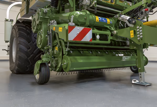 KRONE CombiPack landbruksmaskin fotografert innendørs, viser maskinens grønne konstruksjon og arbeidsbredde. Maskinen har rød og hvit refleksskilt for sikkerhet.