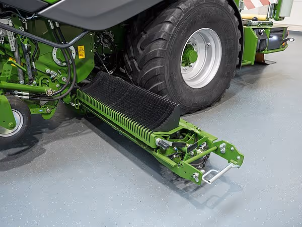 Nærbilde av en grønn KRONE CombiPack HDP landbruksmaskin som viser jordpakkingsenheten med spiralfjærer og store hjul. Maskinen står på et grått gulv innendørs.