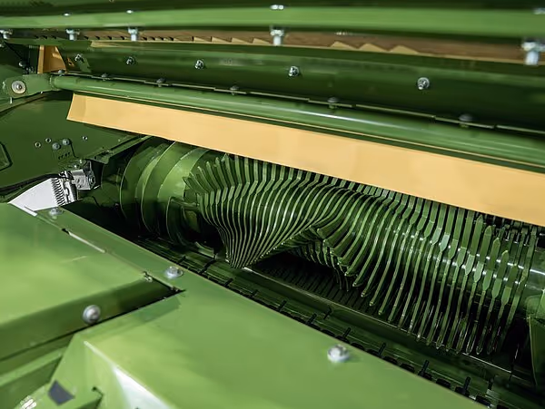 Detaljbilde av en roterende harvetrommel med tette rekker av metalltenner eller pinner for jordbearbeiding. En gul deksel er synlig over mekanismen.