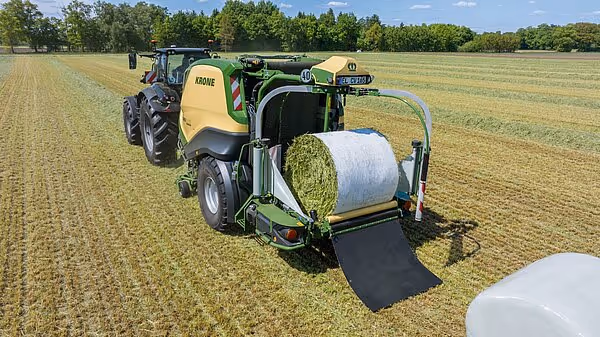 KRONE CombiPack HDP rundballpresse i drift på eng, som viser en ferdig hvit plastinnpakket rundball ved utløpsåpningen.