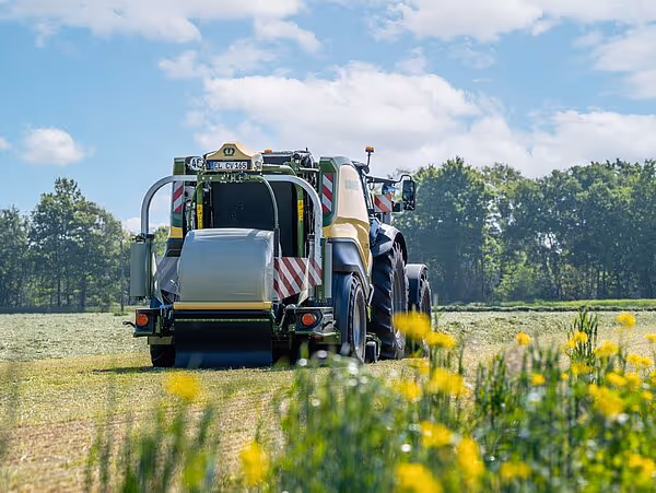 Krone CombiPack HDP traktortrukket landbruksmaskin i arbeid på en åpen mark med gule blomster i forgrunnen.