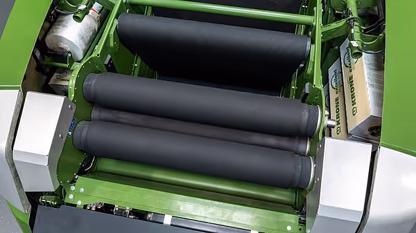 Nærbilde av de sorte pressevalsene på en KRONE Combipack-HDP rundballpresse, montert i grønn maskinramme.